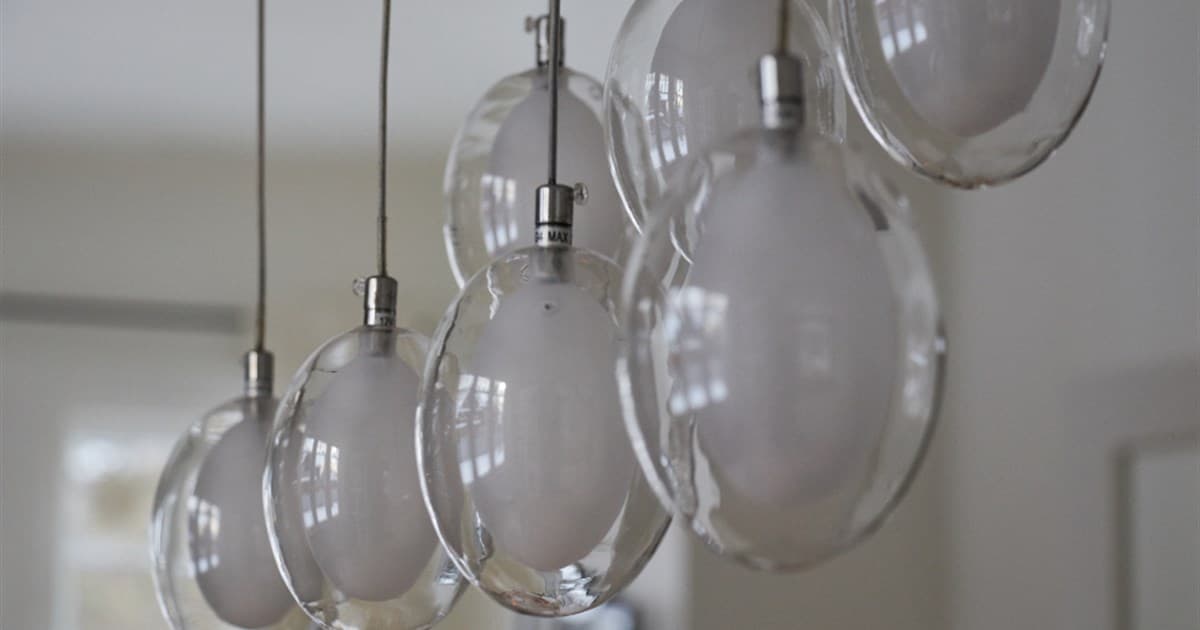 Row of frosted glass pendant light bulbs hanging from thin cables indoors